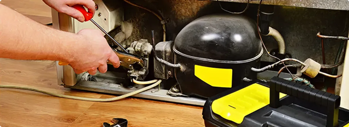 Refrigerator repair technician fixing the compressor and wiring in Mc Farland, WI