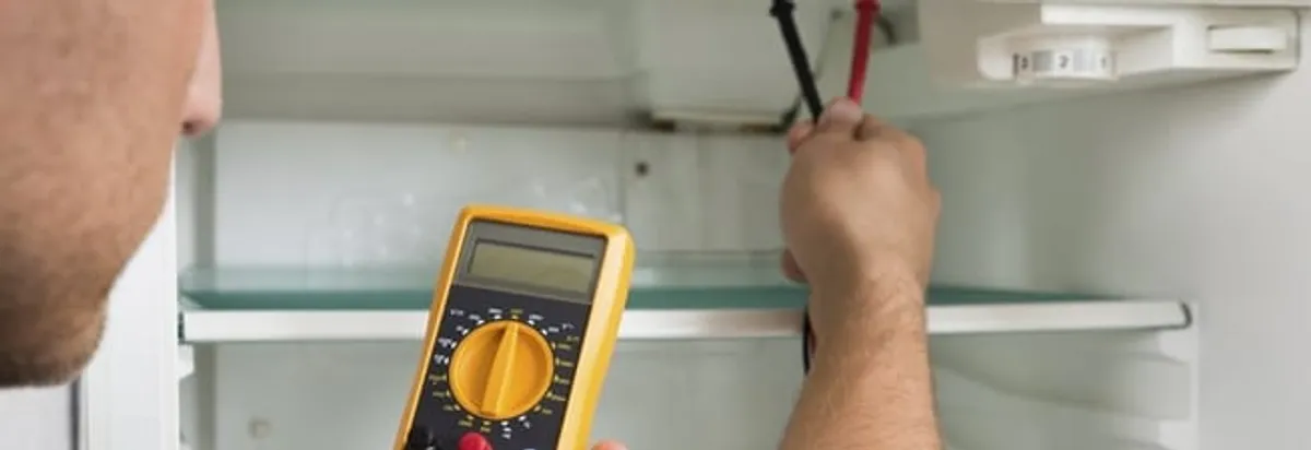 Refrigerator repair technician testing electrical components with a multimeter in Madison, WI